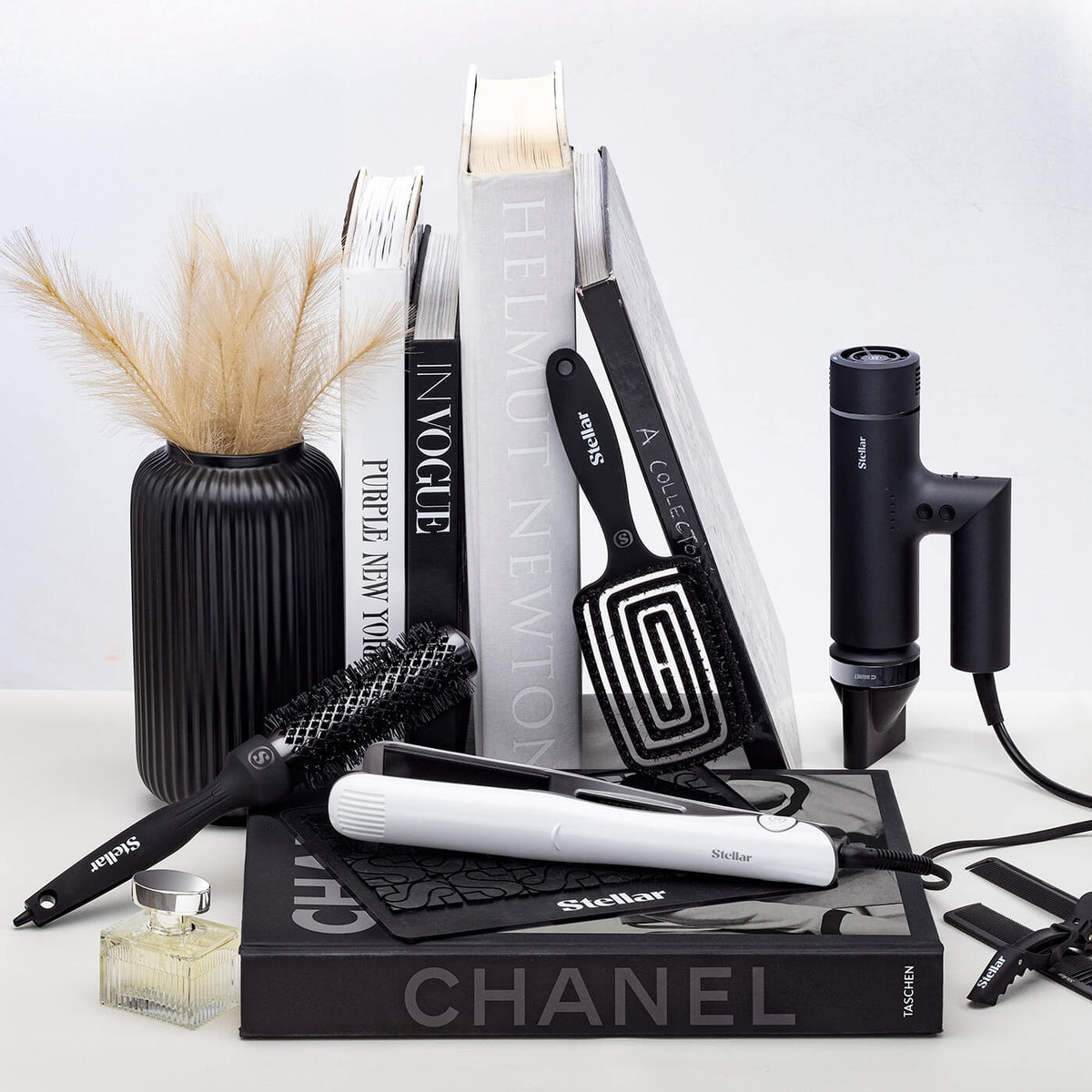 Black OmniFlex hair dryer, white Omnia styler and brushes arranged beside books.