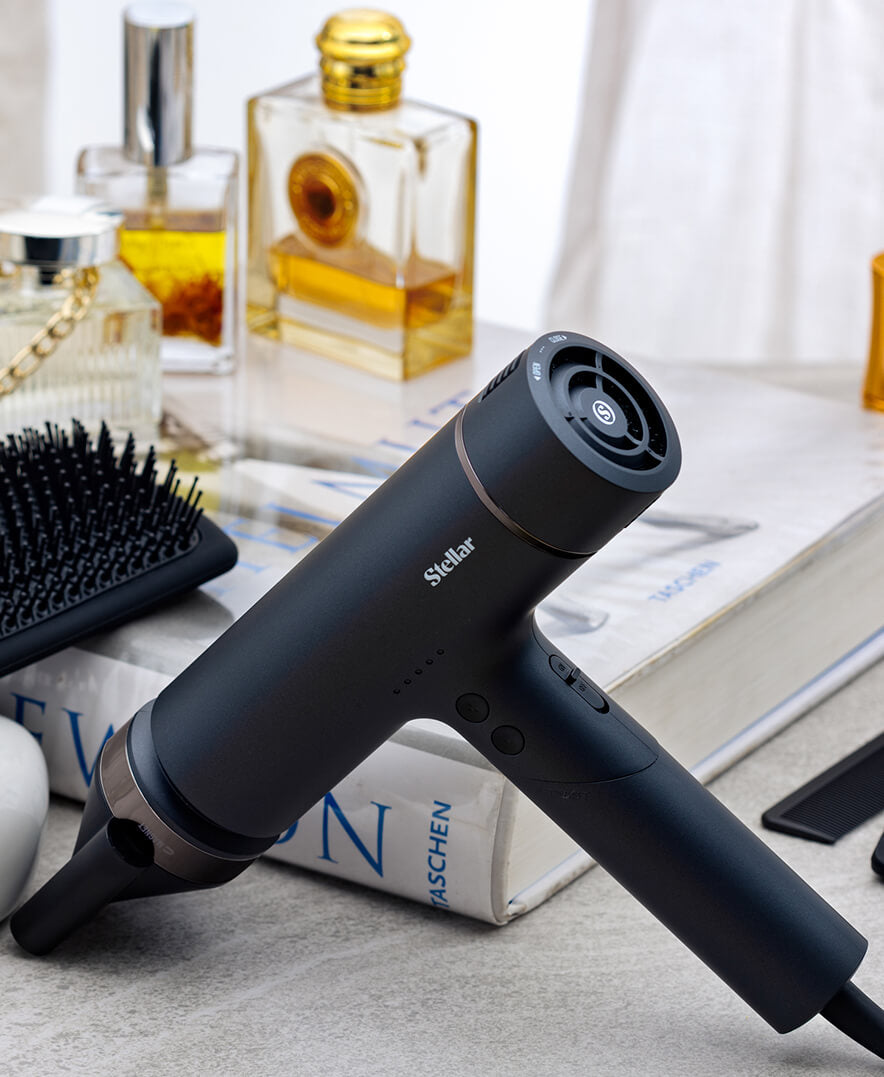 Black OmniFlex hair dryer with concentrator beside a brush and books.
